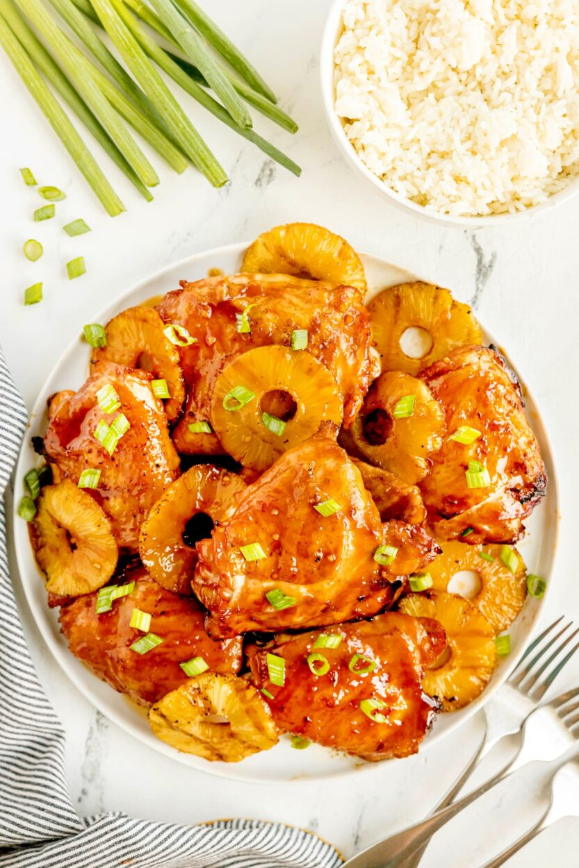 Huli Huli Chicken glazed with sticky pineapple BBQ sauce on a platter garnished with grilled pineapple slices and green onions