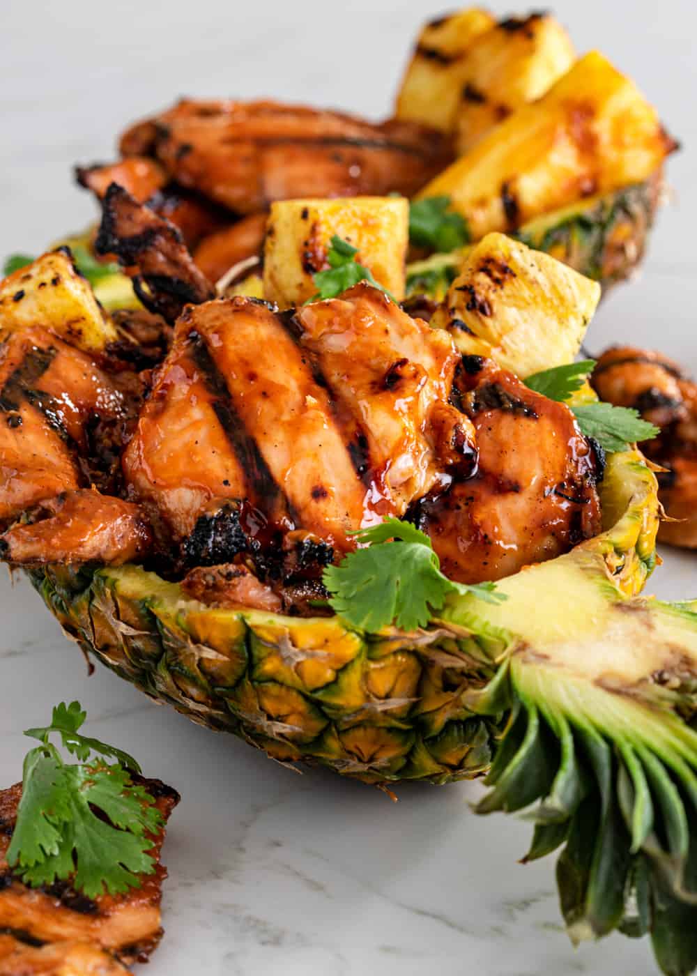 Close-up of Huli Huli Chicken thighs with sticky caramelized glaze, charred grill marks, served with steamed white rice and grilled pineapple