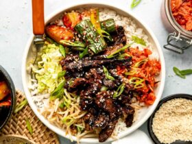 Korean beef bulgogi beautifully plated with steamed rice, lettuce wraps, and traditional banchan side dishes on a wooden table