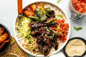 Korean beef bulgogi beautifully plated with steamed rice, lettuce wraps, and traditional banchan side dishes on a wooden table