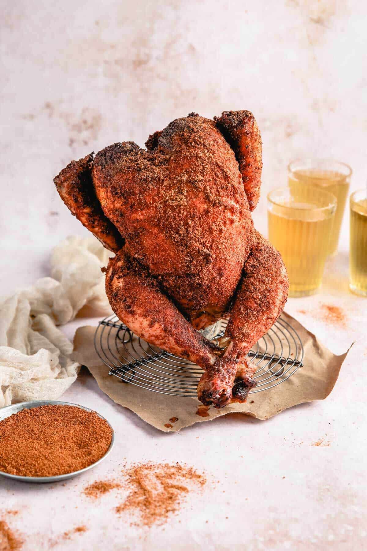Beer Can Chicken process shot — dry rub ingredients in small bowls alongside a raw whole chicken and an open beer can on a prep table