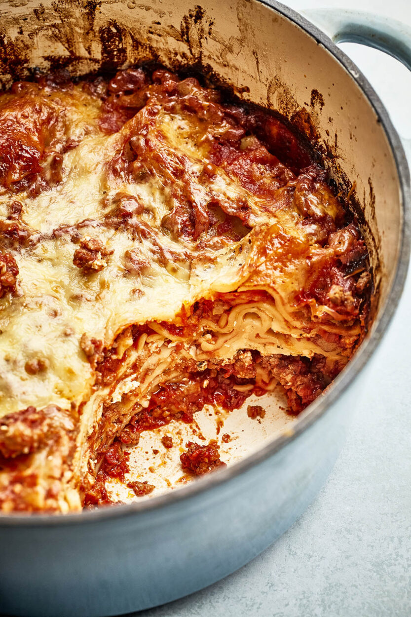 Close-up of Dutch oven lasagna being served with a spatula showing perfectly layered noodles, sausage and melted cheese