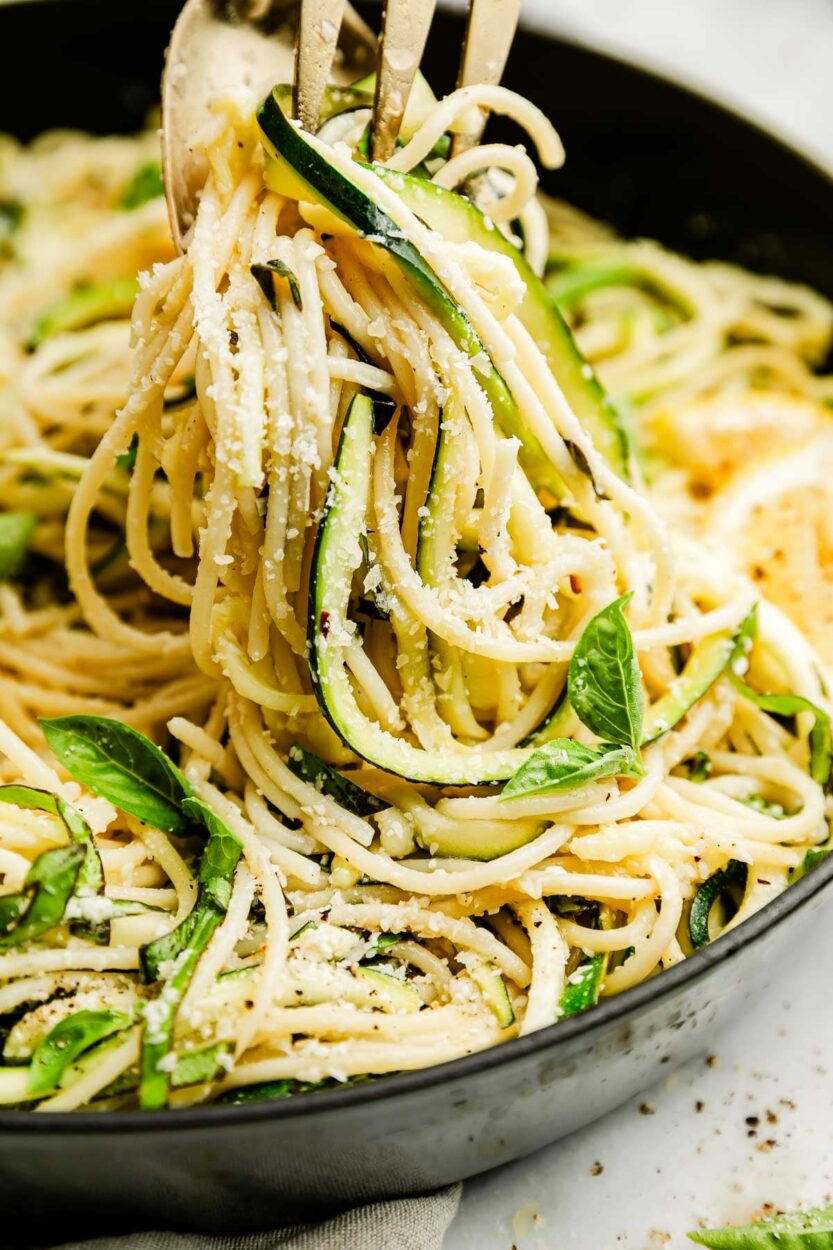 Close-up of Garlic Parmesan Zoodles twirled on a fork, showing the glossy garlic butter sauce, melted Parmesan strands, and fresh basil garnish