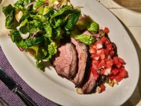 Grilled tri-tip sliced against the grain on a wooden cutting board, showing a smoky charred crust and pink juicy interior, garnished with fresh herbs
