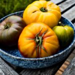 Heirloom tomato galette with golden flaky crust and colorful tomato slices on a rustic wooden board