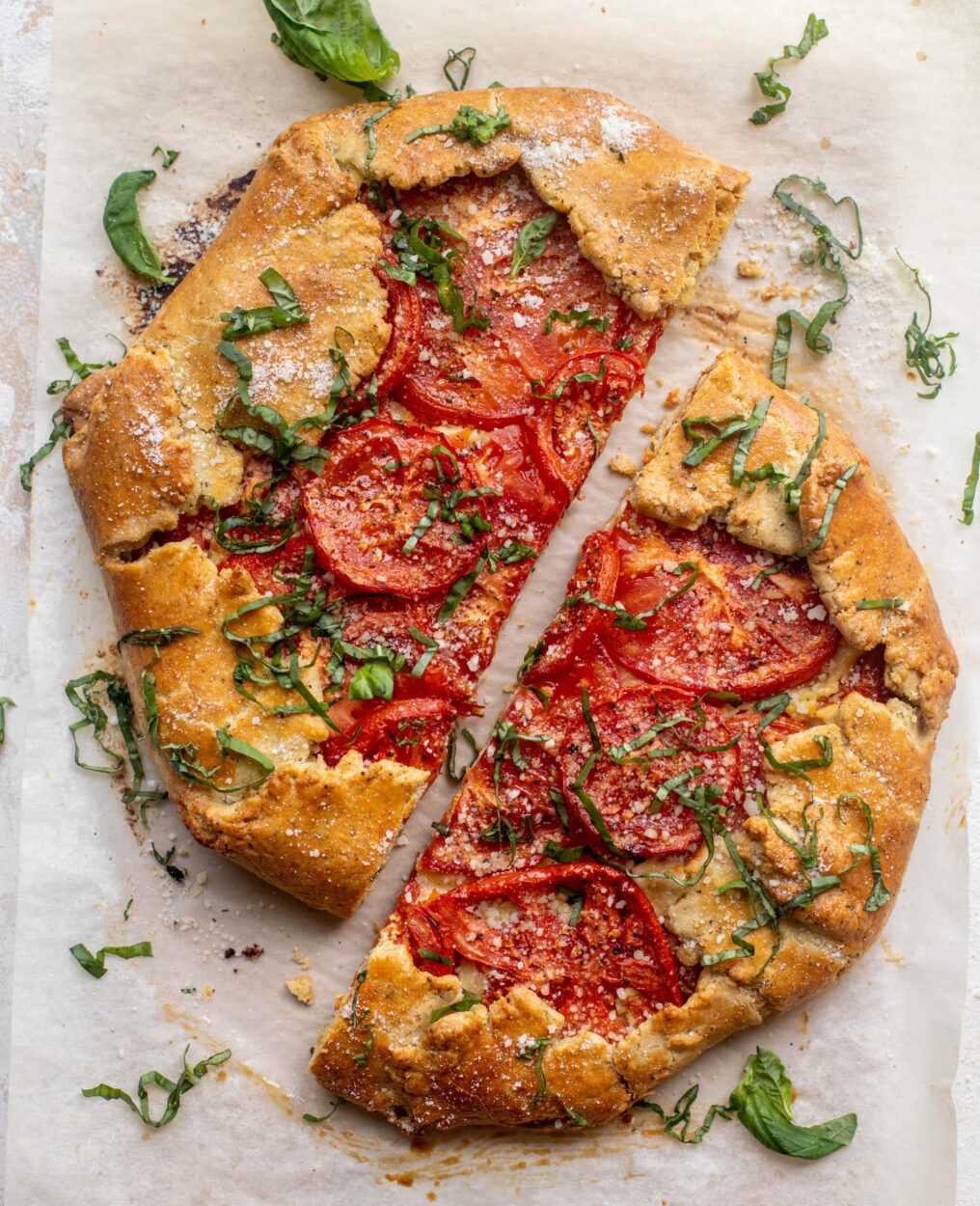 Close-up slice of heirloom tomato galette showing layers of flaky crust, creamy ricotta, and jewel-toned tomatoes with fresh basil