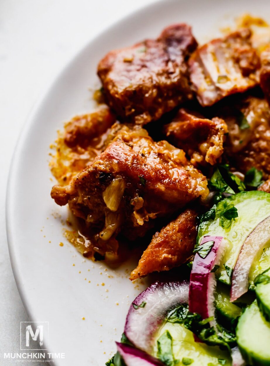 Seasoned pork shoulder pieces in an Instant Pot with orange juice, dried chiles, garlic, and spices visible — overhead flat lay on a dark surface