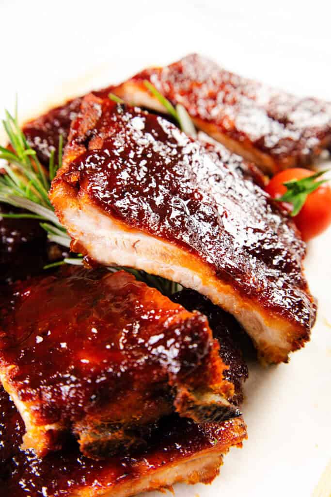 Close-up of Instant Pot baby back ribs glazed with caramelized barbecue sauce, showing fall-off-the-bone texture with meat pulling away from the bone