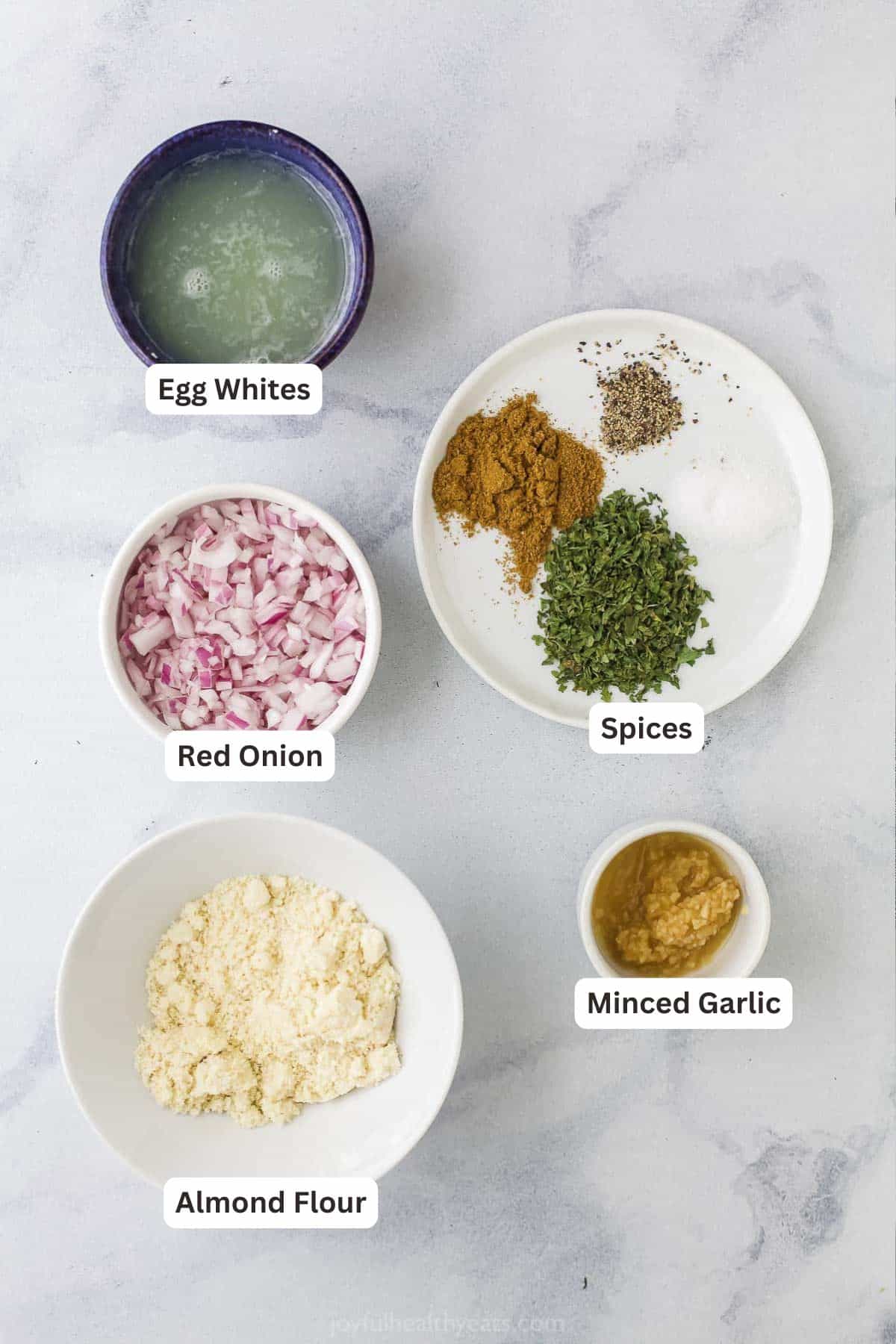Overhead flat lay of ground turkey patties on parchment paper surrounded by fresh garlic, smoked paprika, Dijon mustard, Worcestershire sauce, and a grater with onion