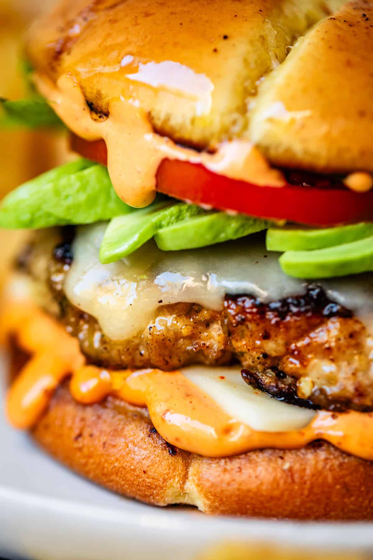 Close-up of a juicy turkey burger cut in half showing a moist, perfectly cooked interior with melted cheese, fresh toppings, and sauce dripping down the side