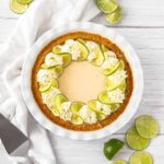 Key Lime Pie with whipped cream and lime slices on a white plate, overhead shot