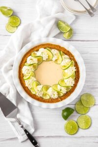 Key Lime Pie with whipped cream and lime slices on a white plate, overhead shot