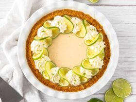 Key Lime Pie with whipped cream and lime slices on a white plate, overhead shot