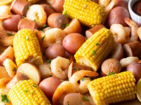 Low Country Shrimp Boil with shrimp, andouille sausage, corn on the cob, and red potatoes dumped on a newspaper-lined table with melted butter and lemon wedges