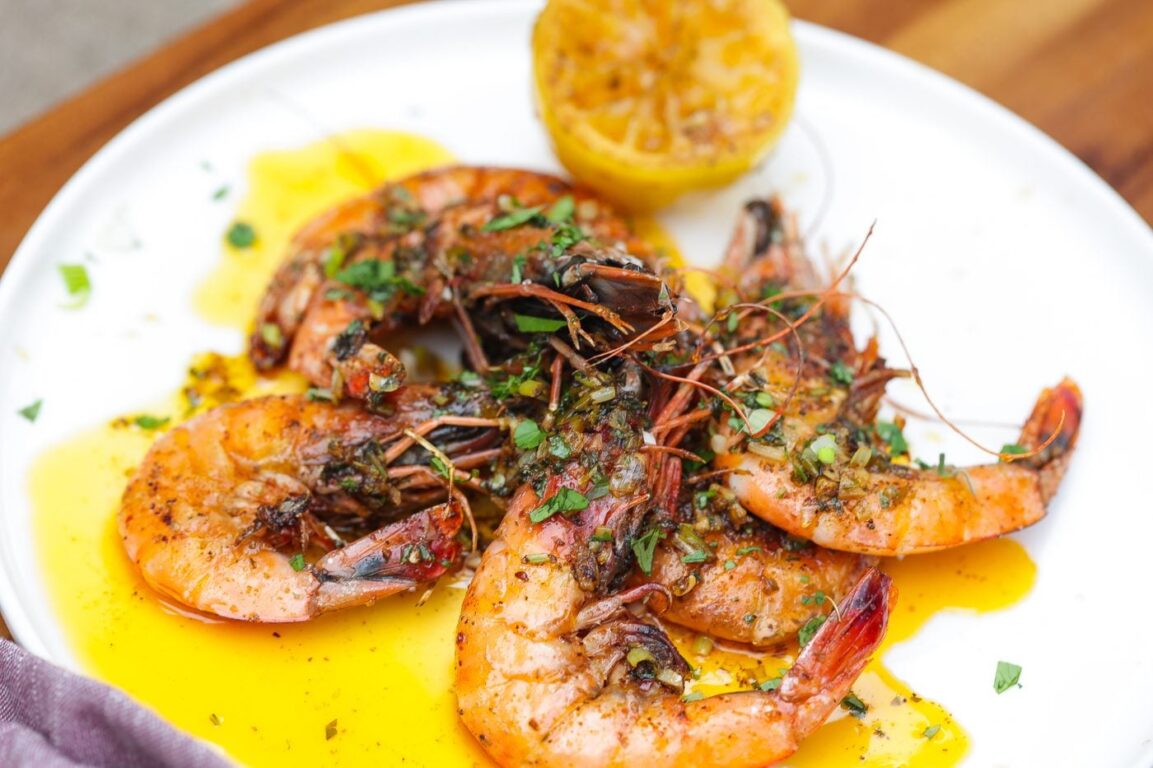 Close-up of Low Country Shrimp Boil served in a white bowl with a lemon wedge, fresh parsley, and melted garlic butter drizzled over the shrimp, corn, and sausage