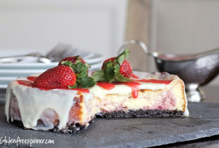 No bake cheesecake with a golden graham cracker crust, topped with fresh strawberries and a glossy berry glaze on a white marble surface