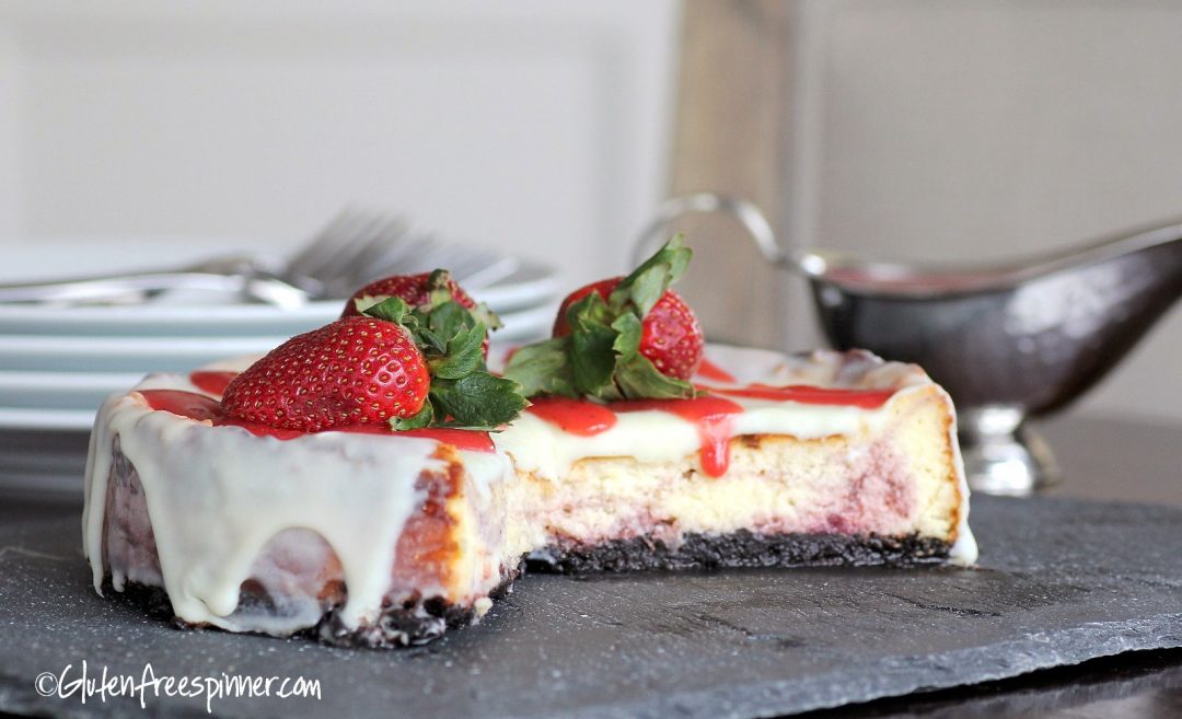 No bake cheesecake with a golden graham cracker crust, topped with fresh strawberries and a glossy berry glaze on a white marble surface