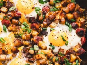 One pan camping breakfast skillet with eggs, crispy potatoes, colorful peppers, and sausage in a cast iron skillet, overhead shot, rustic wooden camp table