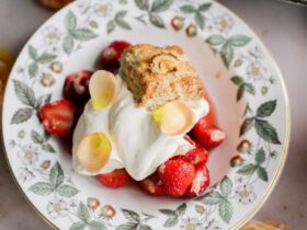 Classic strawberry shortcake with flaky golden biscuits, macerated strawberries and syrup, and billowy whipped cream on a white plate