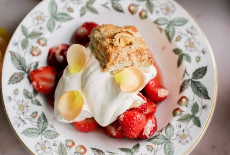 Classic strawberry shortcake with flaky golden biscuits, macerated strawberries and syrup, and billowy whipped cream on a white plate
