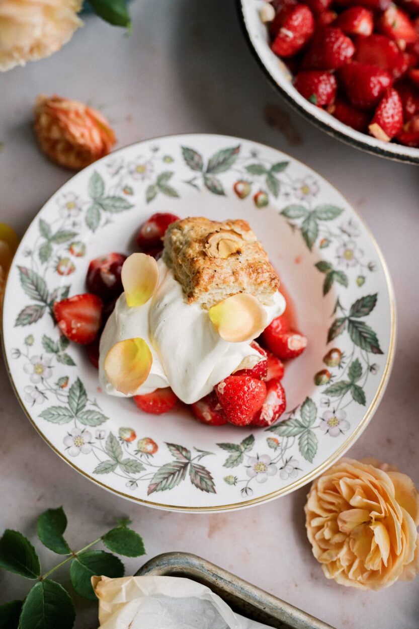 Classic strawberry shortcake with flaky golden biscuits, macerated strawberries and syrup, and billowy whipped cream on a white plate