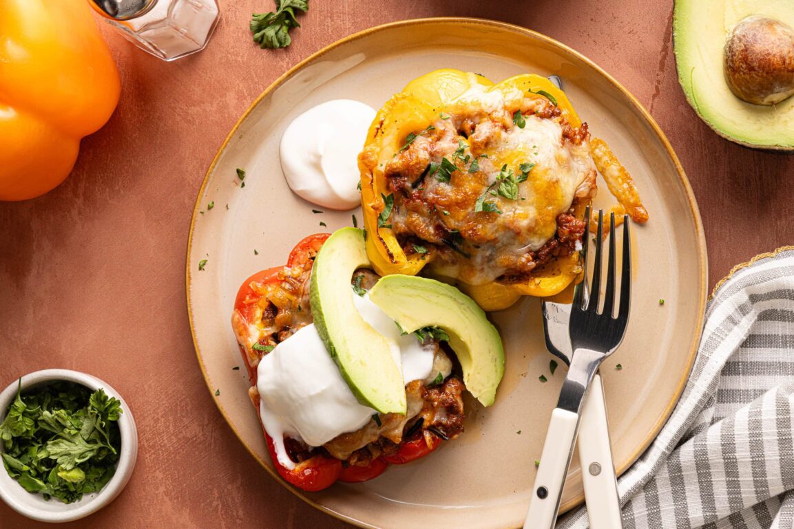 Close-up of a stuffed bell pepper cut open to reveal cheesy ground beef and rice filling, melted cheese pulling away, garnished with fresh parsley