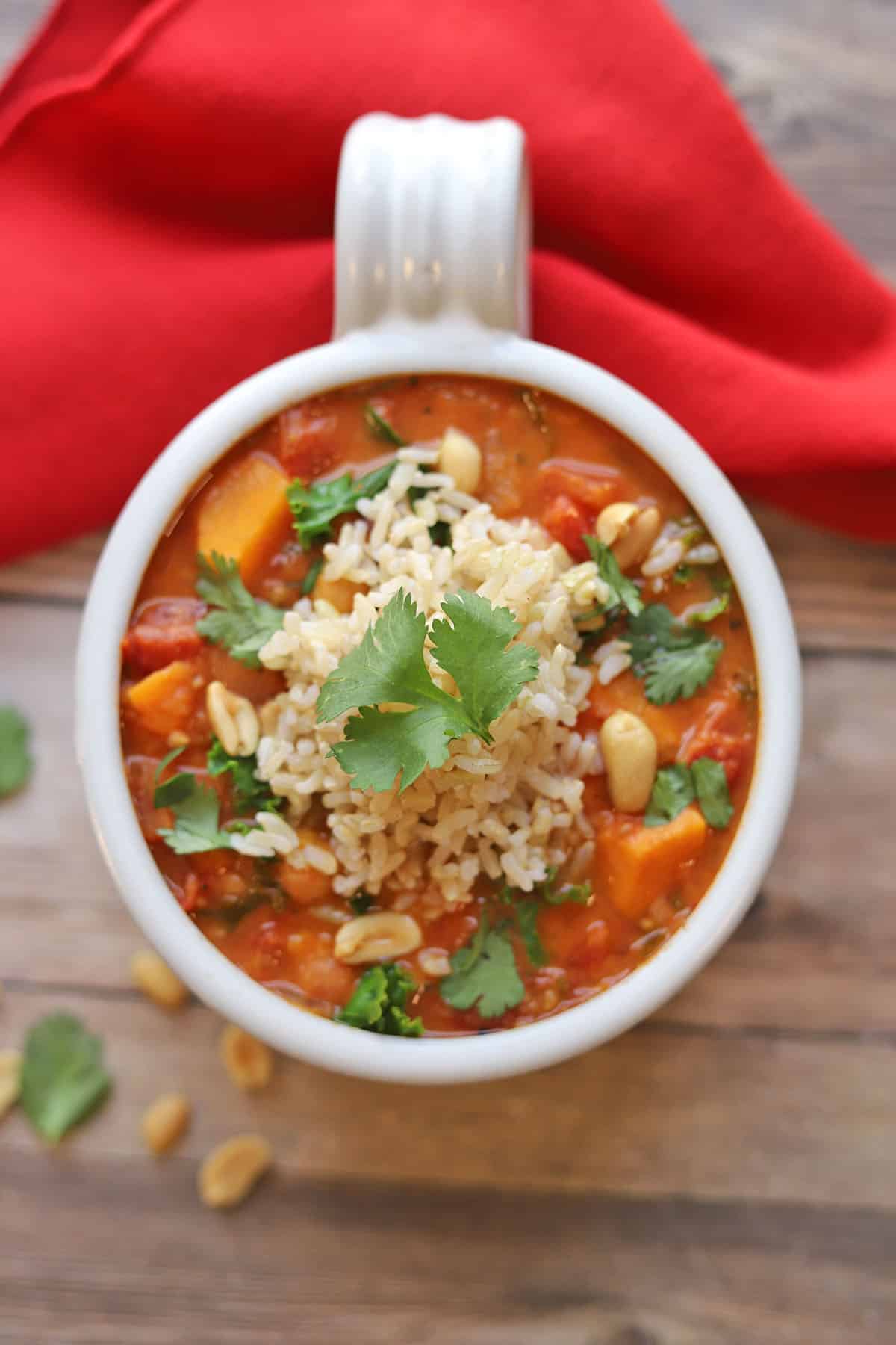 Overhead flat lay of Sweet Potato Peanut Stew ingredients — diced sweet potatoes, chickpeas, peanut butter, fire-roasted tomatoes, ginger, garlic, and spices arranged on a light surface