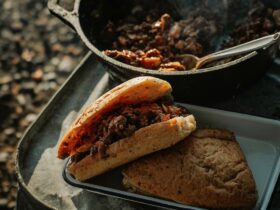 Campfire Sloppy Joes piled high on a toasted brioche bun, served on a rustic tin plate beside a glowing campfire at dusk