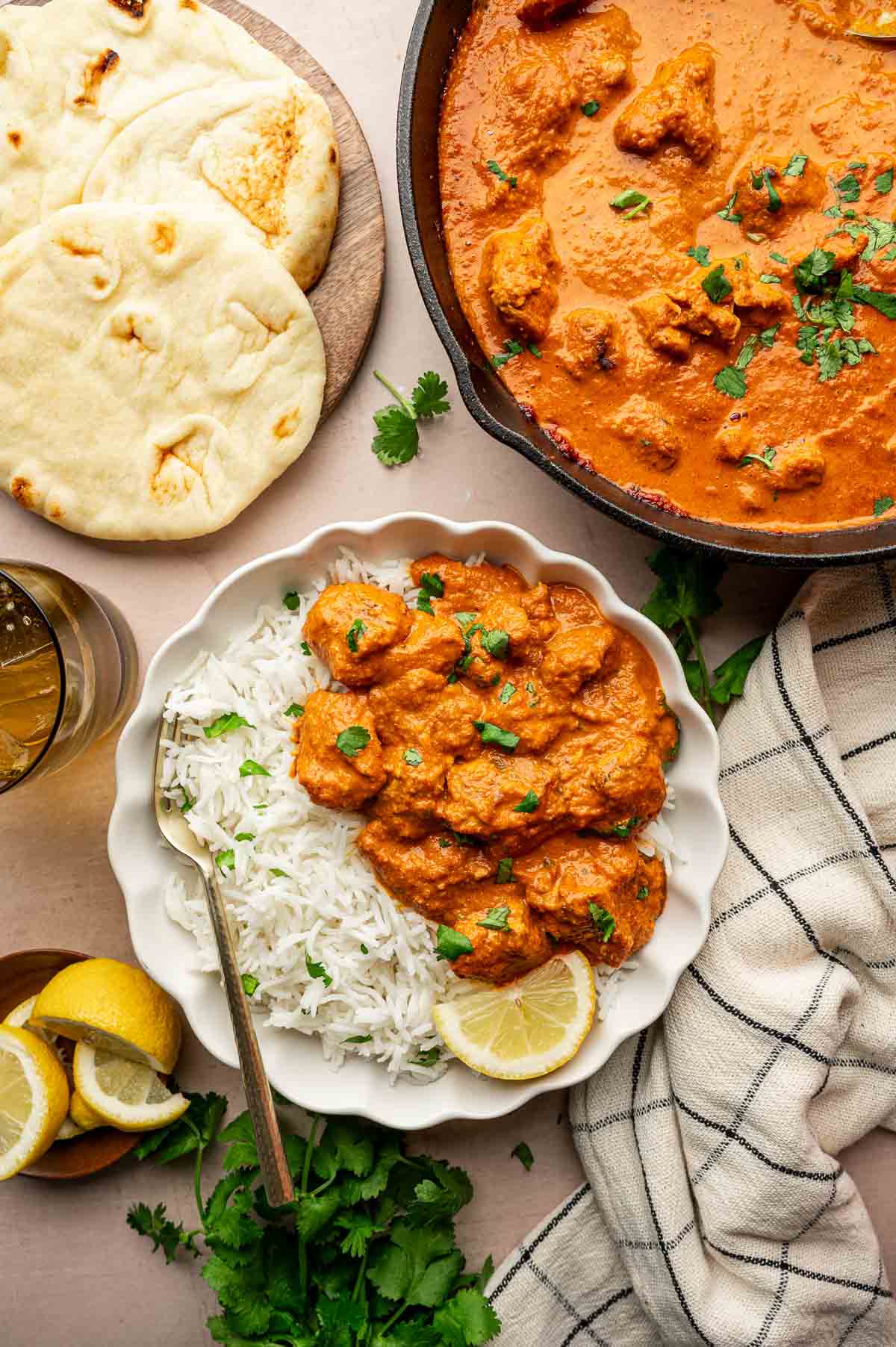 Close-up of Chicken Tikka Masala sauce coating tender pieces of charred chicken, garnished with fresh cilantro and served with a side of warm golden naan
