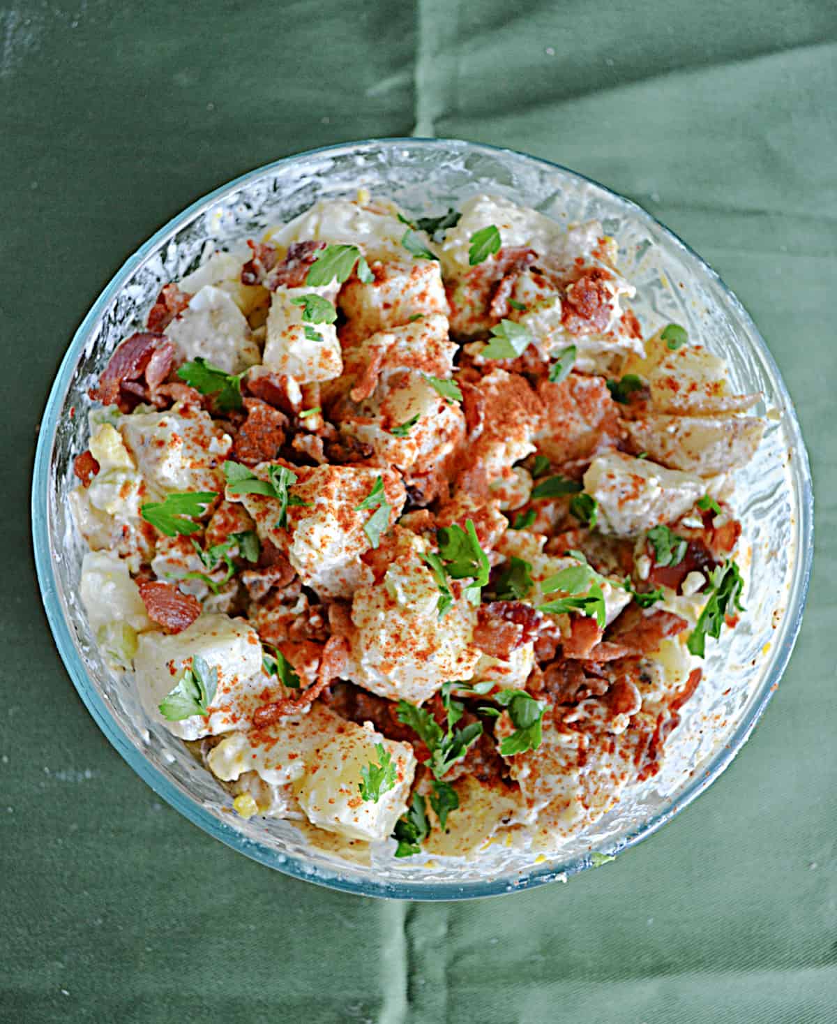 Classic Potato Salad served in a large white bowl, garnished with paprika and fresh chives, surrounded by a wooden picnic table setting