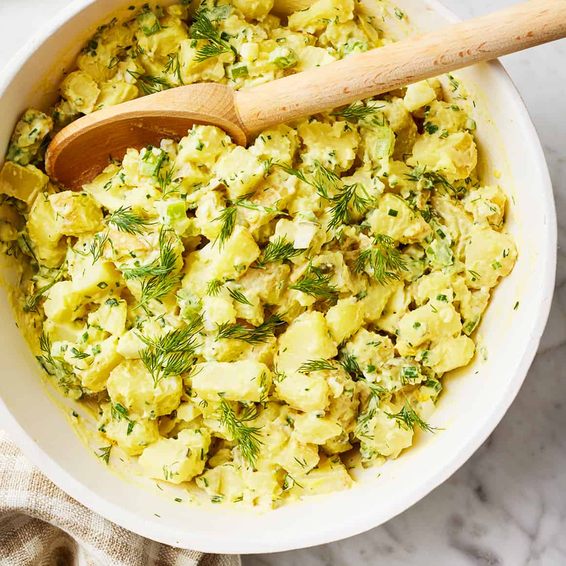 Ingredients for Classic Potato Salad laid out on a wooden surface — Yukon Gold potatoes, eggs, mayo, mustard, celery, pickles, and paprika
