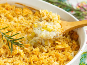 Golden creamed corn casserole in a white baking dish, fresh from the oven with a slightly puffed top and caramelized edges, surrounded by a rustic holiday table setting