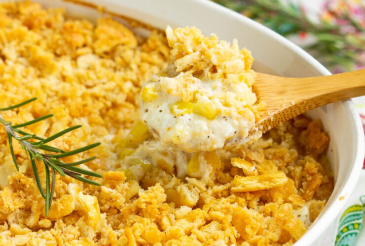 Golden creamed corn casserole in a white baking dish, fresh from the oven with a slightly puffed top and caramelized edges, surrounded by a rustic holiday table setting