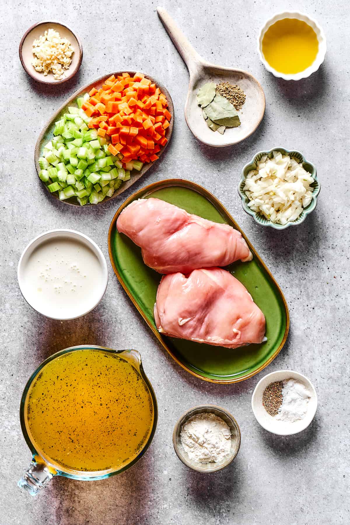 Crockpot Chicken and Dumplings ingredients laid out flat — chicken thighs, cream of chicken soup, vegetables, flour, and fresh herbs on a wooden board