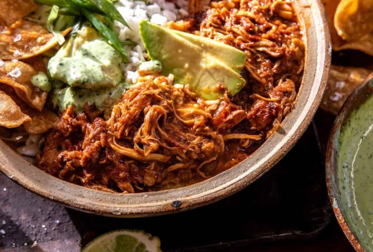 Crockpot Salsa Chicken piled high in a rustic bowl, garnished with fresh cilantro, sliced avocado, and a squeeze of lime, served with warm tortillas on a wooden board