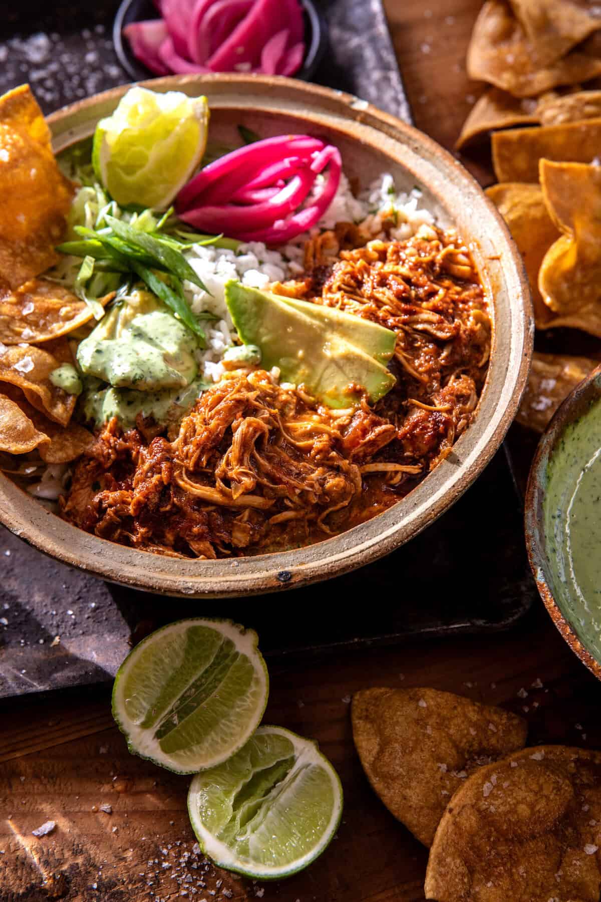 Crockpot Salsa Chicken piled high in a rustic bowl, garnished with fresh cilantro, sliced avocado, and a squeeze of lime, served with warm tortillas on a wooden board