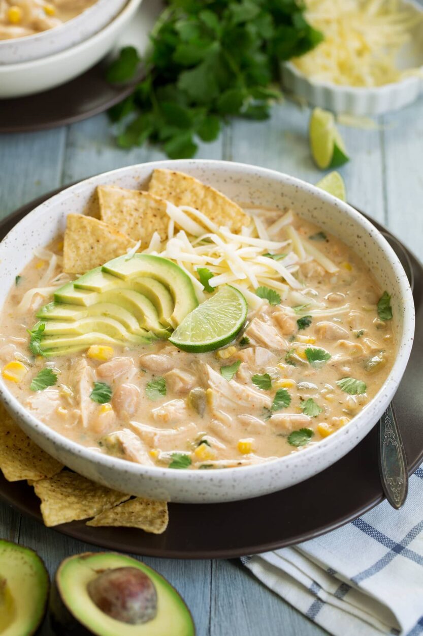 Crockpot white chicken chili ingredients laid out flat — chicken breasts, canned white beans, green chiles, cream cheese block, spices, chicken broth, and garlic on a marble surface