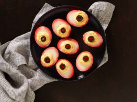 platter of eyeball deviled eggs with bloodshot hot sauce veins and olive pupils on a dark Halloween table