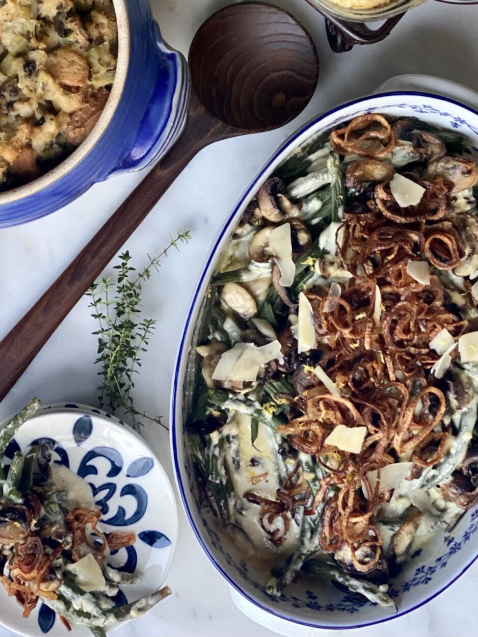 Ingredients for green bean casserole from scratch laid out on a marble surface — fresh green beans, cremini mushrooms, shallots, heavy cream, gruyère cheese, and dry sherry