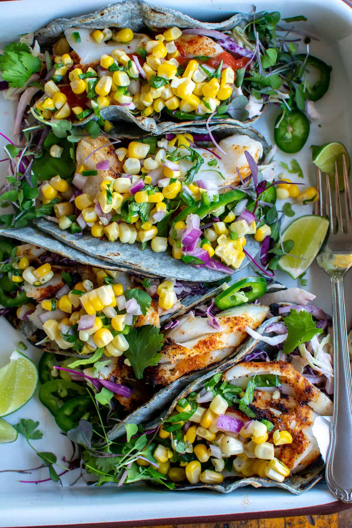 Close-up of a grilled fish taco with corn salsa, showing the flaky charred fish, vibrant salsa, and fresh cilantro against a warm corn tortilla