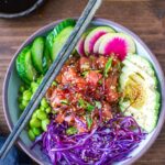Hawaiian Poke Bowl beautifully plated in a white bowl with glossy soy-marinated ahi tuna, avocado slices, edamame, cucumber, pickled ginger, sriracha mayo drizzle, and sesame seeds on sushi rice