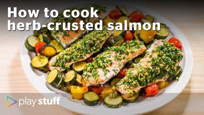 close-up of herb-crusted salmon fillet with golden herb crust, served with roasted cherry tomatoes and zucchini, garnished with a lemon wedge and fresh dill sprigs on a rustic ceramic plate