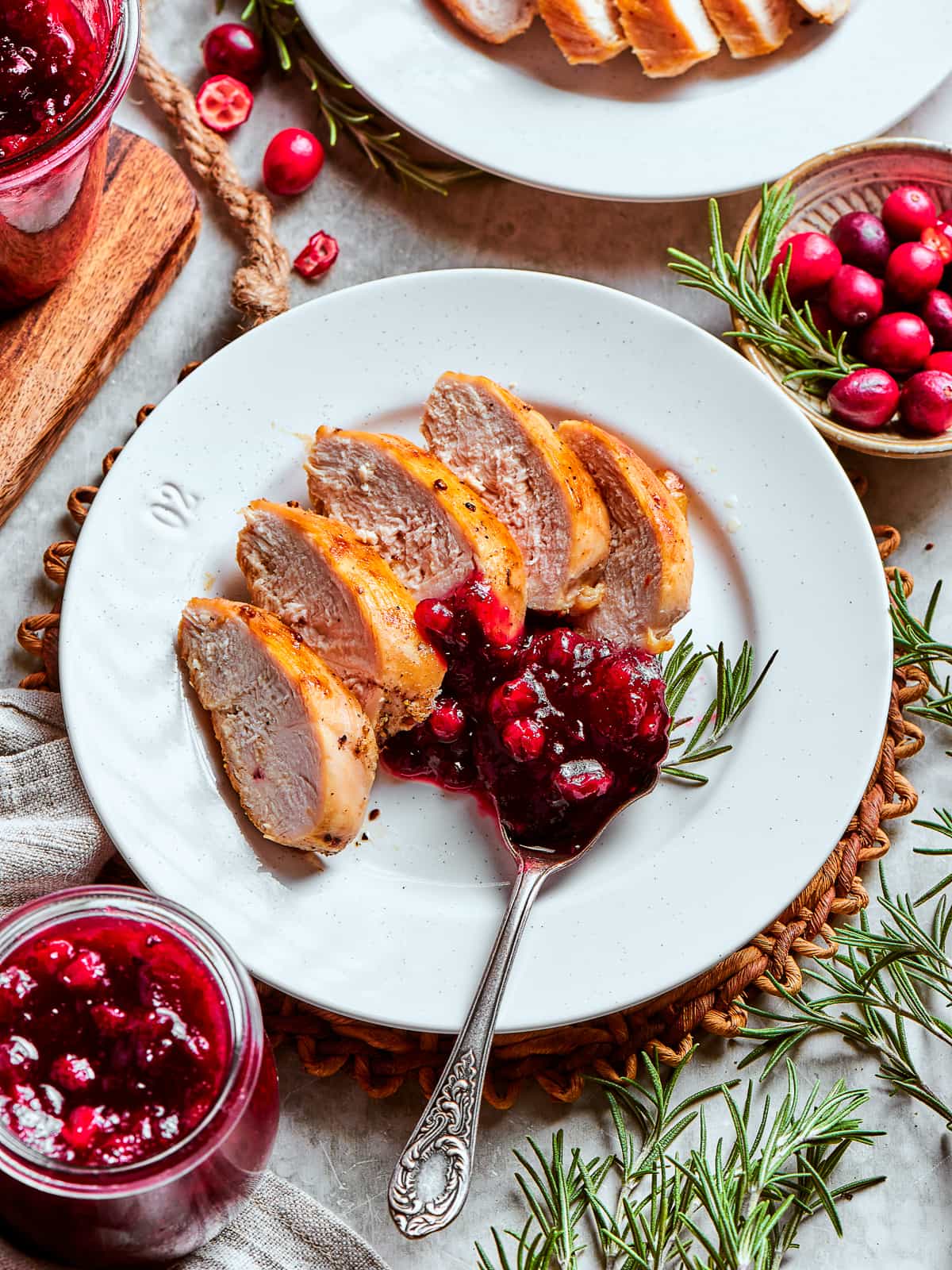 Close-up of glossy homemade cranberry sauce being spooned onto a Thanksgiving plate with turkey and mashed potatoes