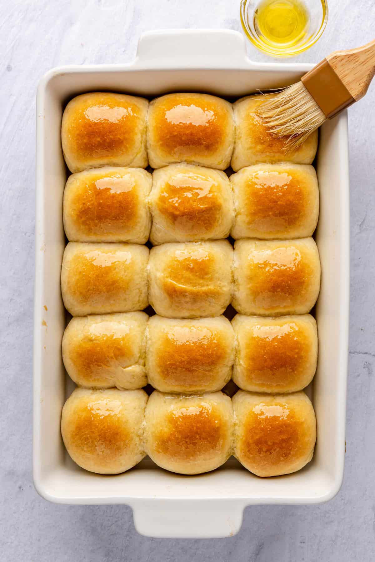 Step-by-step flat lay of honey butter dinner roll ingredients — flour, eggs, butter, honey, milk, and yeast arranged on a marble surface