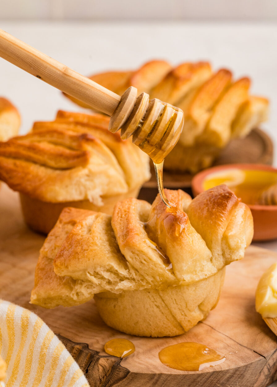 Close-up of a single honey butter dinner roll pulled apart to show the soft, fluffy interior crumb, with honey butter melting on top