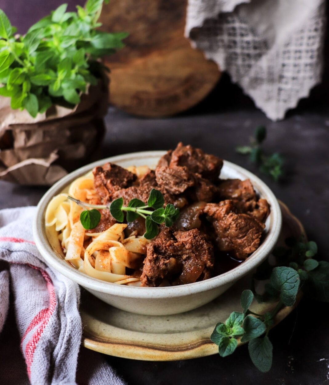 Overhead shot of Hungarian Goulash ingredients laid out — chunks of beef chuck, bowls of sweet and smoked paprika, sliced onions, garlic, tomato paste, caraway seeds, and beef broth on a dark wooden surface