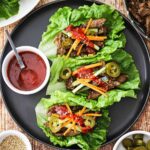 Korean BBQ lettuce wrap bowls beautifully plated on a rustic wooden board with vibrant garnishes, sesame seeds, and dipping sauce