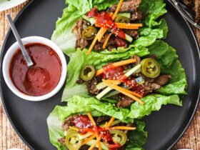 Korean BBQ lettuce wrap bowls beautifully plated on a rustic wooden board with vibrant garnishes, sesame seeds, and dipping sauce