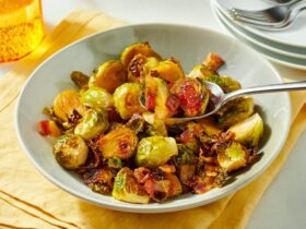 Maple roasted brussels sprouts with bacon on a white serving platter, caramelized and glossy with visible crispy bacon pieces