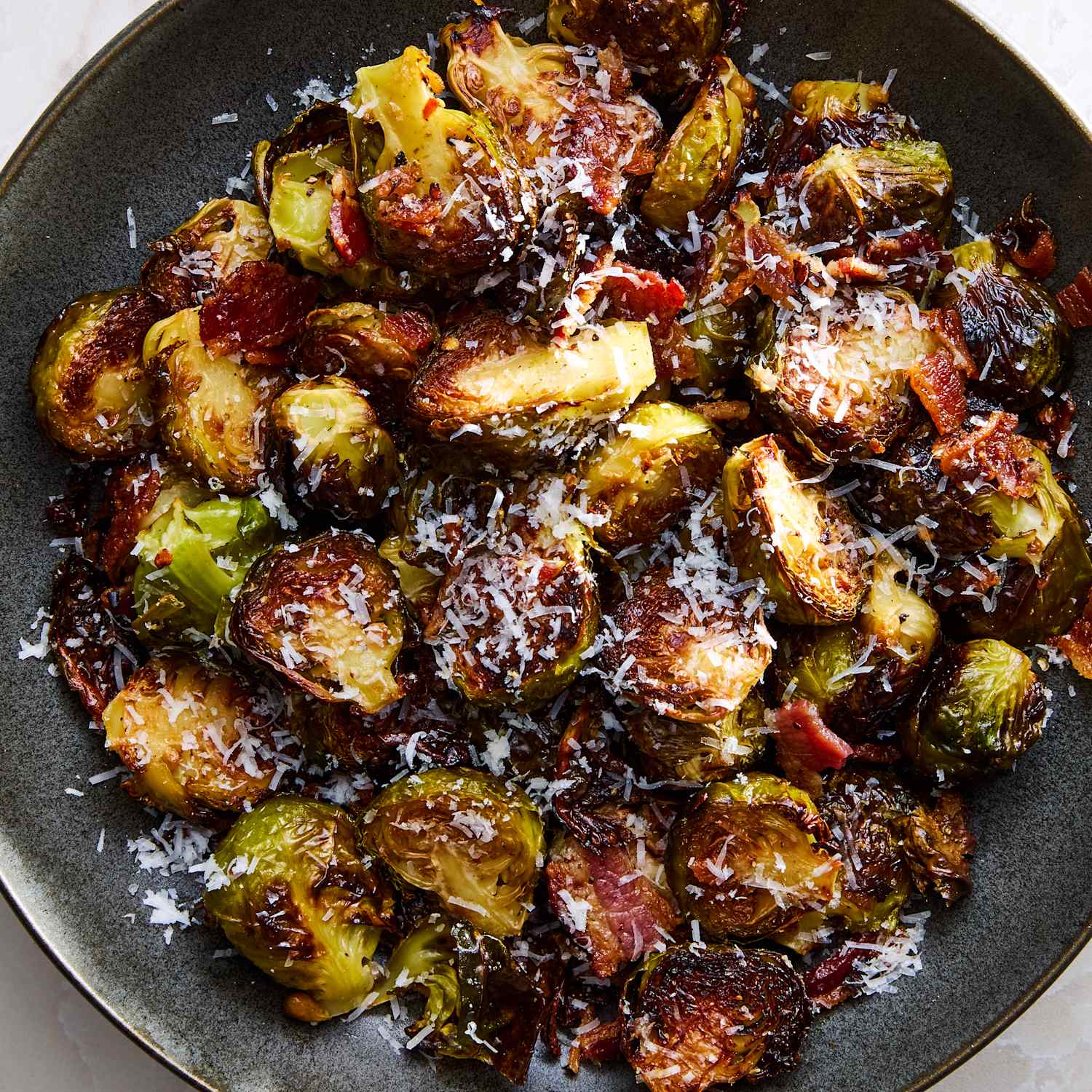 Close-up of maple roasted brussels sprouts with bacon on a sheet pan, showing glossy maple glaze and crispy caramelized edges